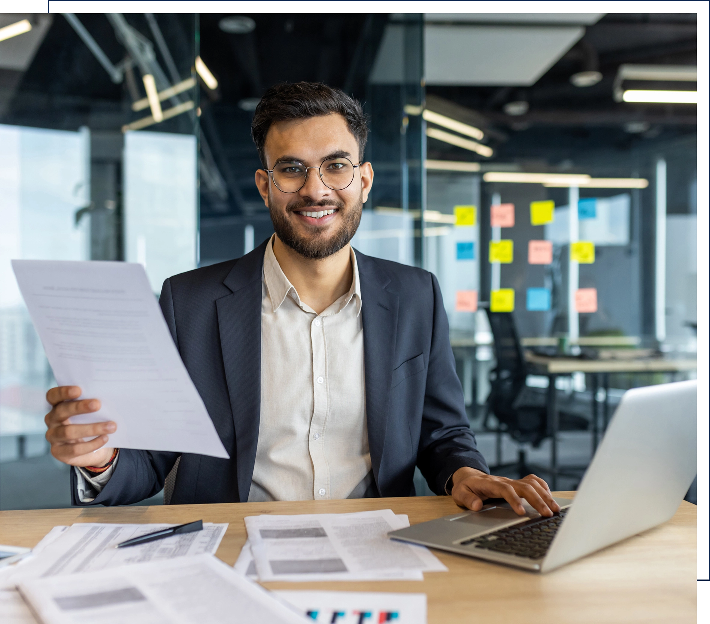 Smiling man working at desk with documents.